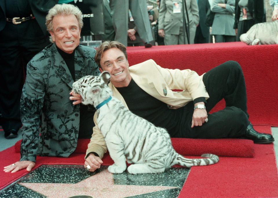 Illusionists Siegfried Fischbacher, left and Roy Uwe Ludwig Horn pose for photographers with a white tiger cub after they unveiled their star on the Hollywood Walk of Fame on Hollywood Boulevard in the Hollywood section of Los Angeles, Calif. Thursday, Sept. 23, 1994. (AP Photo/Neil Jacobs)