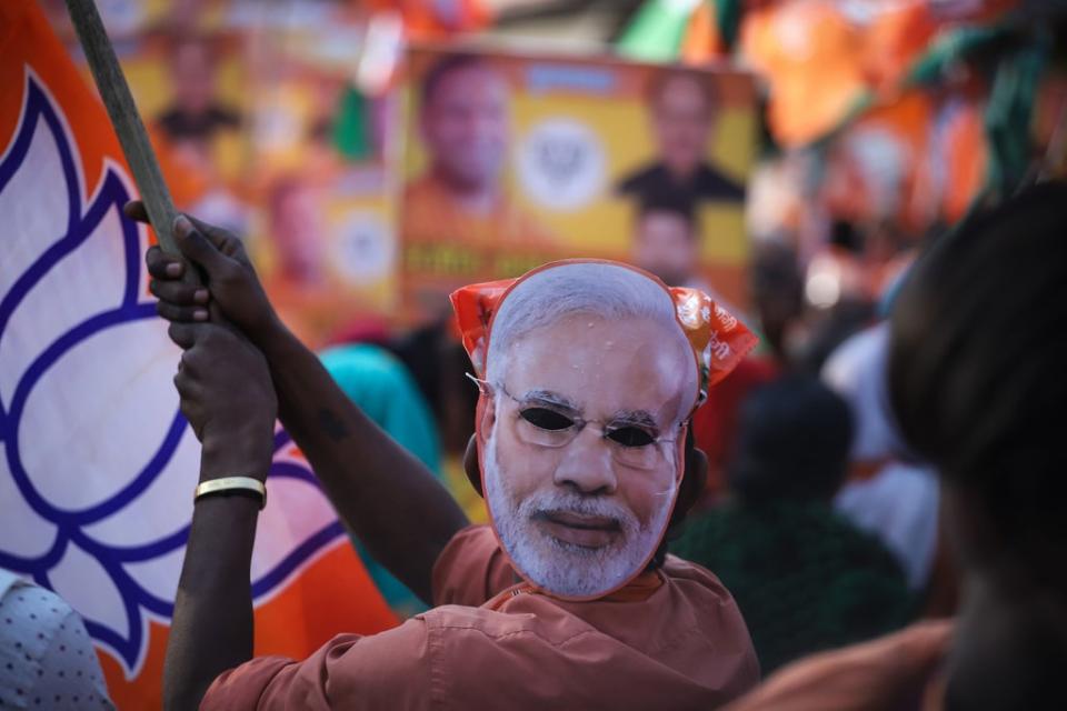 A BJP supporter wears a mask depicting Narendra Modi on the back of his head during a roadshow for Adityanath (Getty)