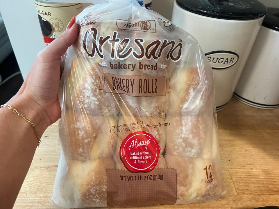 hand holding up a bag of artesano bakery rolls