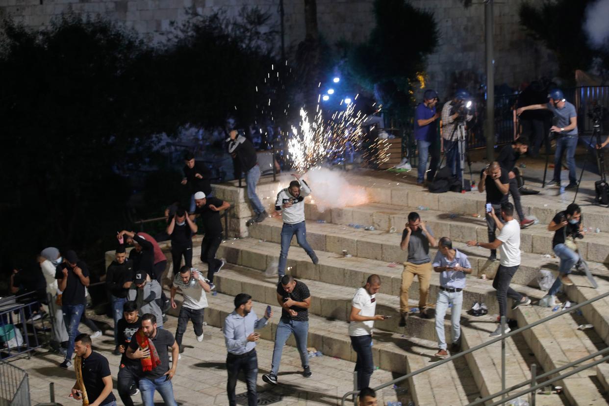 Palestinians run from stun grenades fired by Israeli police officers during clashes at Damascus Gate just outside Jerusalem's Old City on Saturday, May 8, 2021. Israeli police on Saturday clashed with Palestinian protesters outside Jerusalem's Old City during the holiest night of Ramadan, in a show of force that threatened to deepen the holy city's worst unrest in several years.