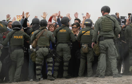 U.S. Customs and Border Protection (CBP) officials move back demonstrators during a gathering in support of the migrant caravan, close to the border wall between the United States and Mexico, as seen from Tijuana, Mexico December 10, 2018. REUTERS/Mohammed Salem