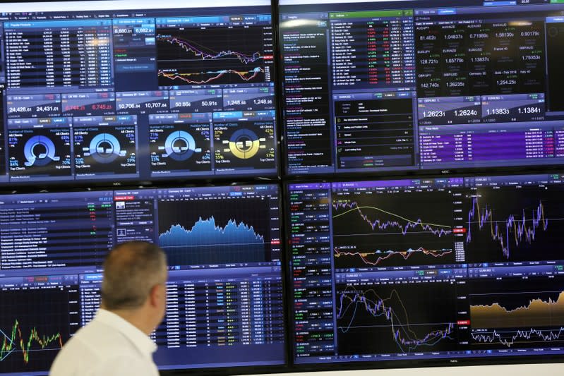 FILE PHOTO: A trader works as a screen shows market data behind him in London