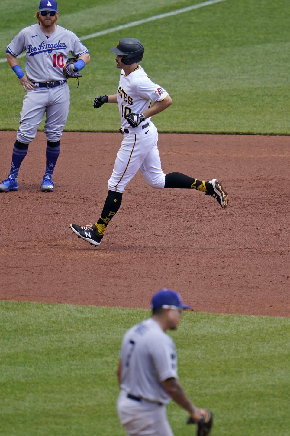 Pittsburgh Pirates' Bryan Reynolds, center, rounds the bases past Los Angeles Dodgers third baseman Justin Turner, left, after hitting a two-run home run off Dodgers starting pitcher Julio Urias, right, during the third inning of a baseball game in Pittsburgh, Thursday, June 10, 2021. (AP Photo/Gene J. Puskar)