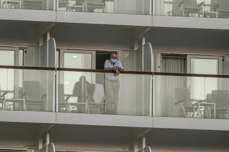 A man wearing a mask to prevent the spread of the coronavirus looks out of the Mein Schiff 6 cruise ship as it is docked at Piraeus port, near Athens on Tuesday, Sept. 29, 2020. Greek authorities say 12 crew members on a Maltese-flagged cruise ship carrying more than 1,500 people on a Greek islands tour have tested positive for coronavirus and have been isolated on board.(AP Photo/Petros Giannakouris)