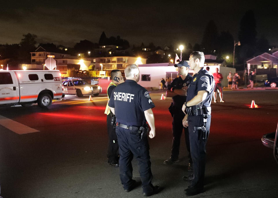 Law enforcement officials stand at a staging area, Friday, Aug. 10, 2018, at the ferry terminal in Steilacoom, Wash., near where a Coast Guard spokeswoman said the agency was responding to a report of a smoke plume and possible plane crash. Earlier in the evening, officials at Seattle-Tacoma International Airport said an Alaska Airlines plane had been stolen and later crashed. (AP Photo/Ted S. Warren)