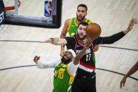 Utah Jazz guard Mike Conley (10) lays the ball up while guarded by Portland Trail Blazers center Jusuf Nurkic (27) during the first half of an NBA basketball game Thursday, April 8, 2021, in Salt Lake City. (AP Photo/Isaac Hale)
