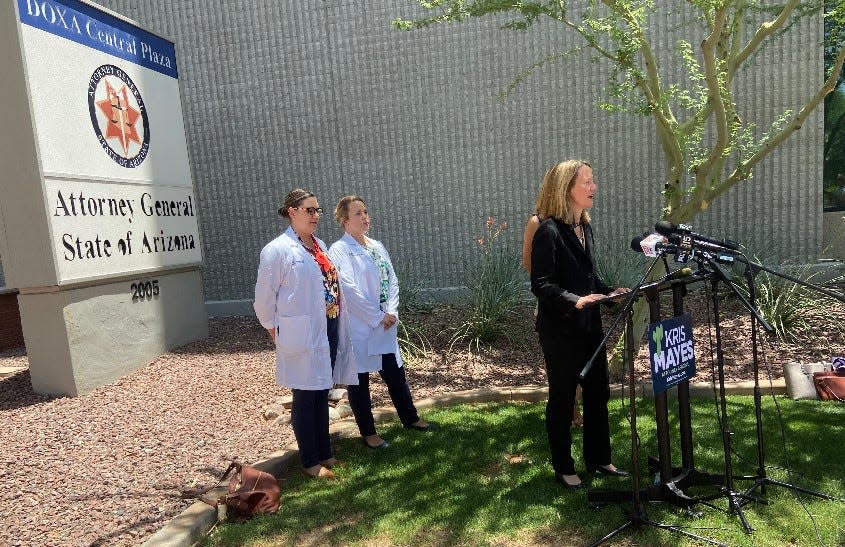 Democratic attorney general candidate Kris Mayes (right) speaks to the press in front of the Arizona Attorney General's Office in Phoenix on June 30, 2022.