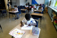 Caleb Taylor, 5, front, works on his art work during a class at Chalmers Elementary school in Chicago, Wednesday, July 13, 2022. America's big cities are seeing their schools shrink, with more and more of their schools serving small numbers of students. Those small schools are expensive to run and often still can't offer everything students need (now more than ever), like nurses and music programs. Chicago and New York City are among the places that have spent COVID relief money to keep schools open, prioritizing stability for students and families. But that has come with tradeoffs. And as federal funds dry up and enrollment falls, it may not be enough to prevent districts from closing schools. (AP Photo/Nam Y. Huh)