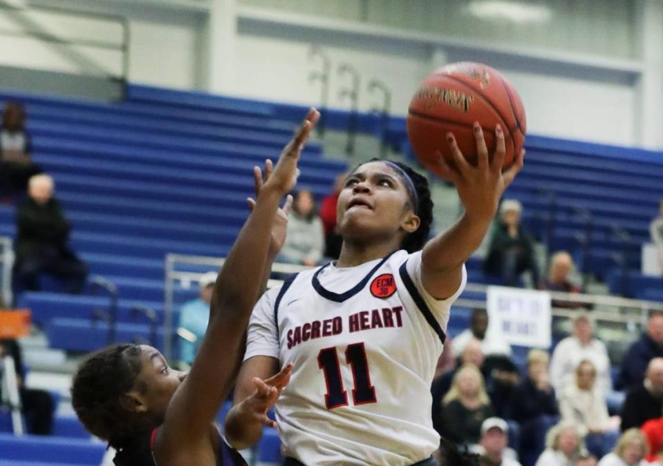 Sacred Heart’s ZaKiyah Johnson (11) shoots under the basket against Manual’s Lexi Weaver (1) during the Girls LIT Championship at the Valley High School gym in Louisville, Ky. on Jan. 28, 2023.