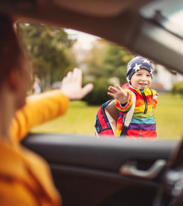 little boy waving to adult in a car