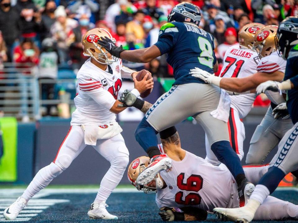 Seattle Seahawks defensive end Carlos Dunlap (8) leaps over San Francisco 49ers guard Tom Compton (66) on his way to sacking quarterback Jimmy Garoppolo (10) for a safety in the third quarter of an NFL game on Sunday at Lumen Field in Seattle.