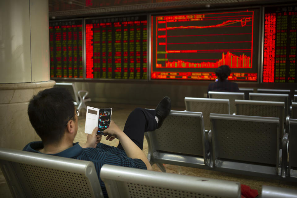 A Chinese investor uses his smartphone as he monitors stock prices at a brokerage house in Beijing, Friday, April 19, 2019. Asian stock indexes rose moderately in quiet holiday trading on Good Friday as some markets were closed. (AP Photo/Mark Schiefelbein)