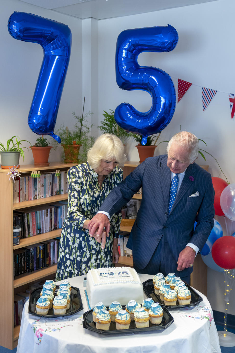 Britain's King Charles III and Queen Camilla cut a commemorative cake during their visit to the Royal Infirmary of Edinburgh, to celebrate 75 years of the NHS at NHS Lothian, as part of the first Holyrood Week since his coronation, Scotland, Tuesday July 4, 2023. (Jane Barlow/Pool Photo via AP)