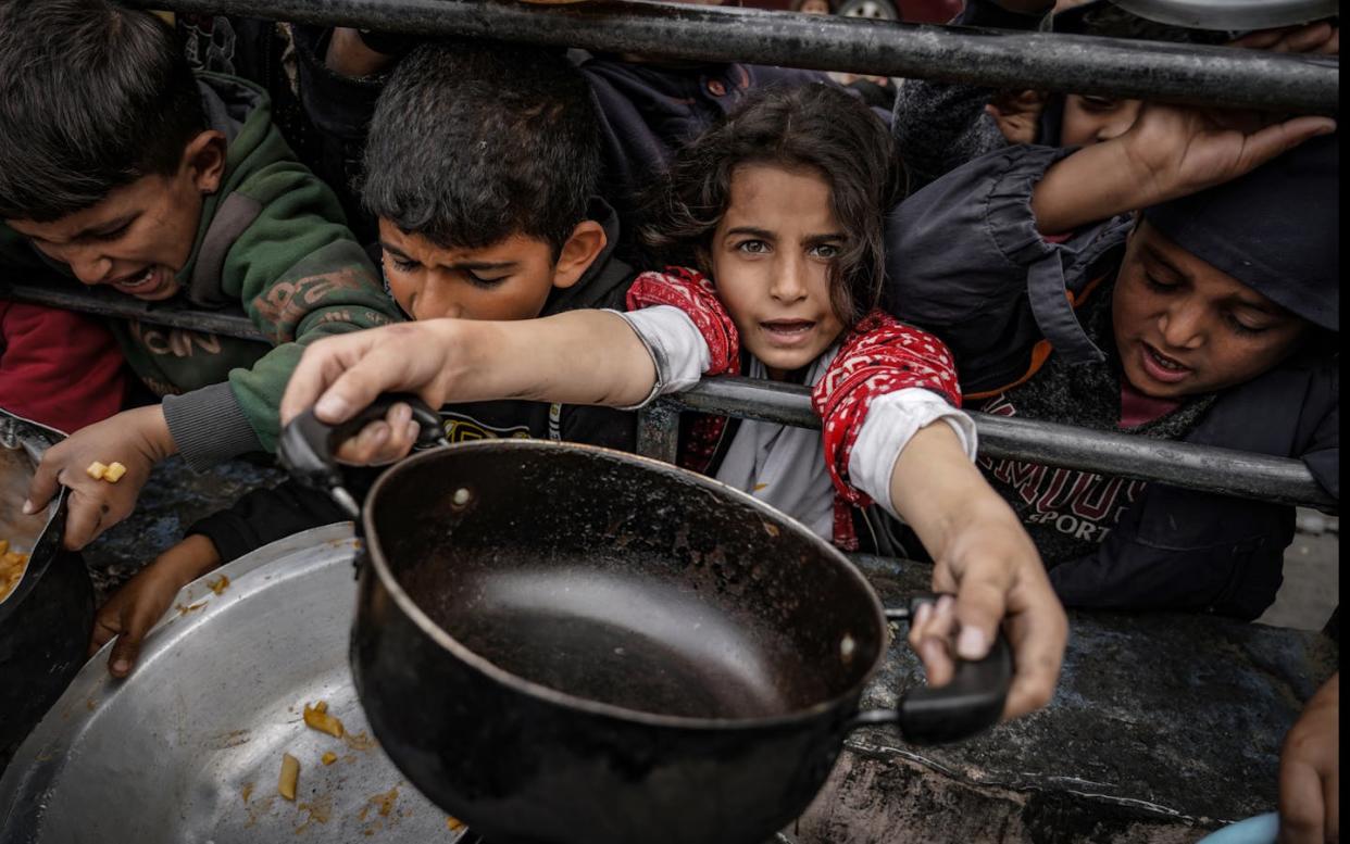 Displaced Gazan children wait in line to receive food. <a href="https://www.gettyimages.com/detail/news-photo/palestinian-children-holding-empty-pots-2-wait-in-line-to-news-photo/1993688681?adppopup=true" rel="nofollow noopener" target="_blank" data-ylk="slk:Belal Khaled/Anadolu via Getty Images;elm:context_link;itc:0;sec:content-canvas" class="link ">Belal Khaled/Anadolu via Getty Images</a>