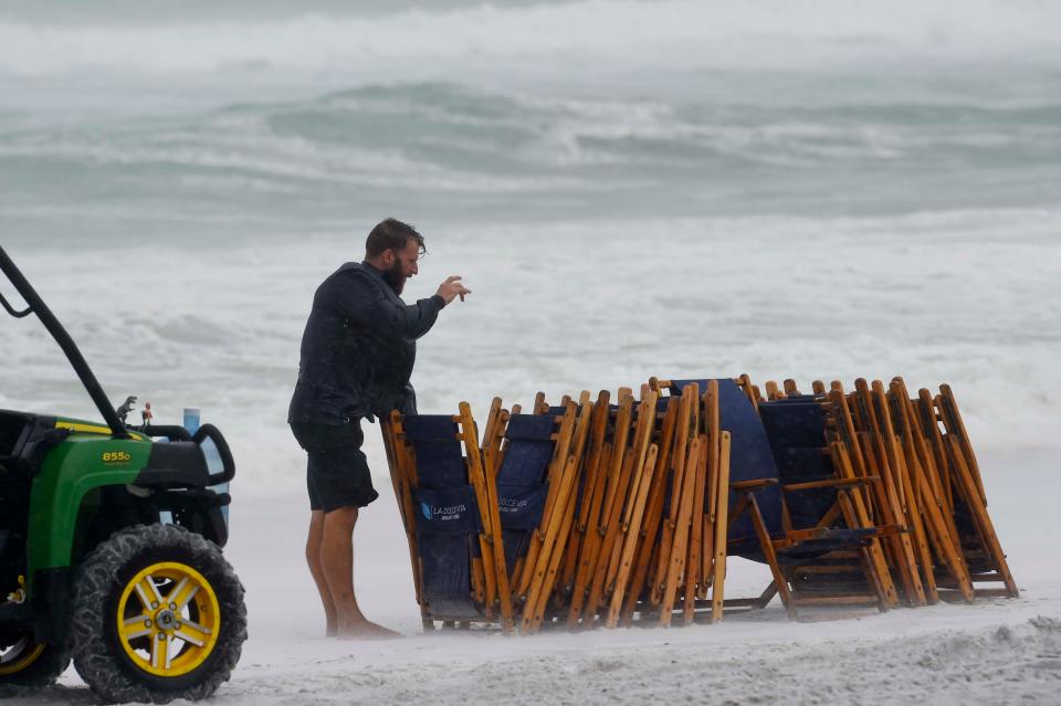 A beach vendor with La Docle Vita stacks up beach chairs to remove them before a storm in September 2018. Walton County commissioners next month are expected to consider proposed changes to the county's beach activities ordinance.
