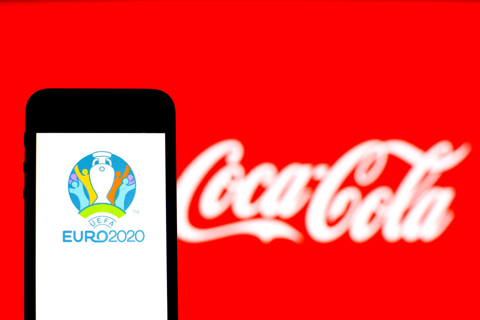 UEFA Euro 2020 logo seen displayed on a smartphone with a Coca-Cola logo in the background.