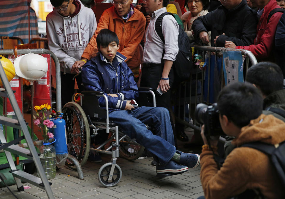 FILE - In this Dec. 5, 2014, file, photo, student leader Joshua Wong attends a news conference as he sits on a wheel chair during a hunger strike at the occupied area outside government headquarters in Hong Kong. Overseas, Joshua Wong has emerged as a prominent face of Hong Kong's months-long protests for full democracy. At home, he is just another protester. (AP Photo/Kin Cheung, File)