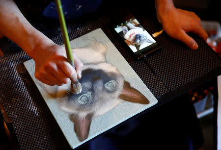 A painter paints a portrait of a pet cat at the Pet Rainbow Festa, a pet funeral expo targeting an aging pet population, in Tokyo, Japan September 18, 2017. REUTERS/Kim Kyung-Hoon