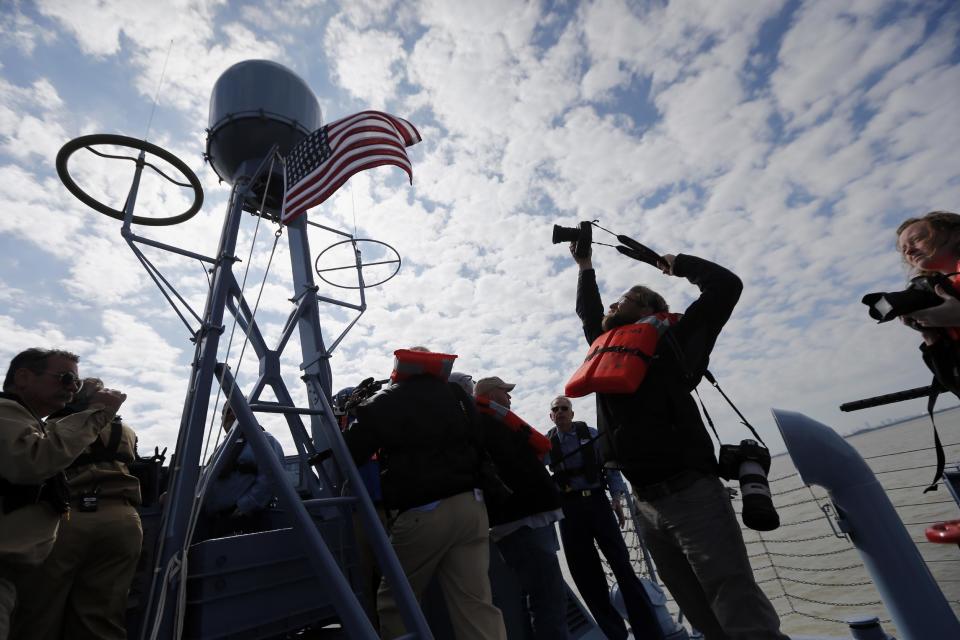 A photographer takes photo of a flag during a media ride of the PT 305, which was restored by the National WWII Museum, on Lake Pontchartrain, where she was originally tested by Higgins Industries more than 70 years ago, in New Orleans, Thursday, March 16, 2017. The U.S. Navy PT boat that sank three vessels and saw action in Europe in World War II is back in New Orleans where it was built, what historians describe as the nation's only fully restored combat ship of that type from the era. Its return to water is the culmination of a 10-year restoration project by the museum. (AP Photo/Gerald Herbert)