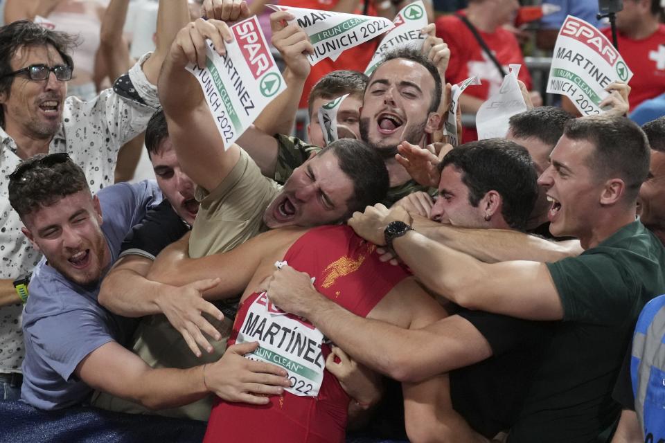 Asier Martinez, of Spain, is hugged by his supporters after winning the gold medal in the Men's 110 meters hurdles during the athletics competition in the Olympic Stadium at the European Championships in Munich, Germany, Wednesday, Aug. 17, 2022. (AP Photo/Matthias Schrader)