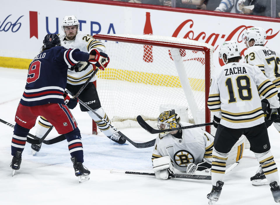 Boston Bruins' Parker Wotherspoon (29) grabs the puck in front of Winnipeg Jets' Alex Iafallo (9) during the second period of an NHL hockey game Friday, Dec. 22, 2023, in Winnipeg, Manitoba. (John Woods/The Canadian Press via AP)