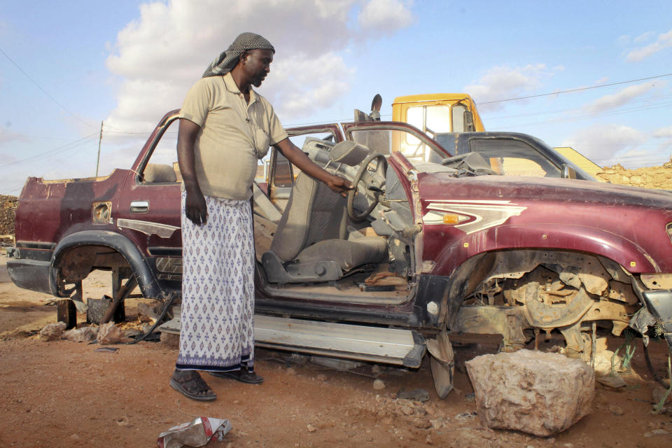 In this photo taken Monday, Sept. 17, 2012, Somali pirate Mohamed Jama shows the remains of his car, after he was forced to sell its parts to raise income for daily expenses, in the once-bustling pirate town of Galkayo, Somalia. The empty whisky bottles and overturned, sand-filled skiffs that litter this shoreline are signs that the heyday of Somali piracy may be over - most of the prostitutes are gone, the luxury cars repossessed, and pirates talk more about catching lobsters than seizing cargo ships. (AP Photo/Farah Abdi Warsameh)