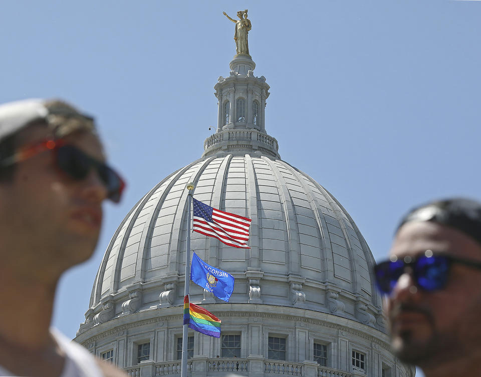 FILE - In this June 7, 2019 file photo, Clay Thomas, left, and Yosh Mayans, supporters of the Lesbian, Gay, Bisexual, Transgender and Queer (LGBTQ) community, converse outside the Wisconsin State Capitol after a rainbow flag observing Pride Month was raised over the east wing of the building in Madison, Wis. The display, endorsed by Democratic Gov. Tony Evers, drew backlash from conservative Republican lawmakers. (John Hart/Wisconsin State Journal via AP, File)