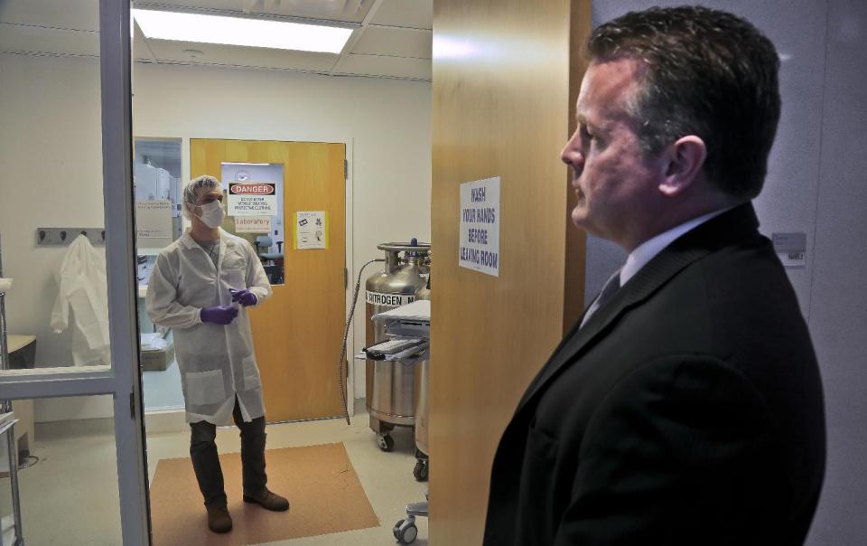 In this April 15, 2014 photo, Mark Desire, right, assistant director for forensic biology at the Office of Chief Medical Examiner, talks with forensic criminalist Michael Mosco as he prepares to enter the bone grinding room at the Office of Chief Medical Examiner in New York. The room is central to the examination of bone DNA from those who died on Sept. 11, 2001. Forensic scientists are still trying to match the bone with DNA from victims who have never been identified. (AP Photo/Bebeto Matthews)