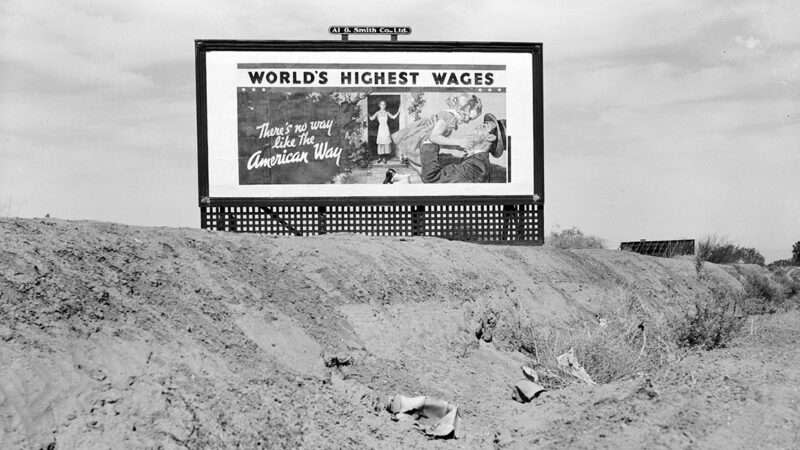 A black and white photo of a billboard reading 'World's highest wages: There is no way like the American way'