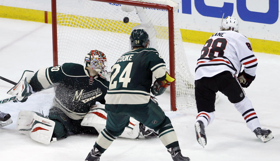 The game-winning shot by Chicago Blackhawks right wing Patrick Kane (88) gets past Minnesota Wild goalie Ilya Bryzgalov, left, of Russia, in front of Wild left wing Matt Cooke (24) during overtime of Game 6 of an NHL hockey second-round playoff series in St. Paul, Minn., Tuesday, May 13, 2014. The Blackhawks won 2-1. (AP Photo/Ann Heisenfelt)