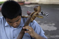 In this Dec. 11, 2012 photo, a young musician tunes his cello, made from recycled materials, during a practice session with "The Orchestra of Instruments Recycled From Cateura" in Cateura, a vast landfill outside Paraguay's capital of Asuncion, Paraguay. Children from the orchestra use instruments fashioned out of recycled materials taken from a landfill where their parents eke out livings as trash-pickers, and about 20 of them regularly perform the music of Beethoven and Mozart, Henry Mancini and the Beatles. (AP Photo/Jorge Saenz)