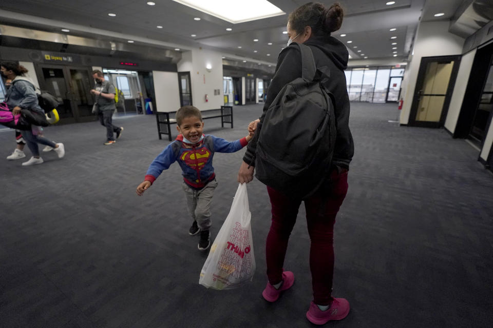 Yancarlos Amaya, 5, a migrant from Honduras, spins around his mother, Celestina Ramirez, during a layover at George Bush International Airport, Wednesday, March 24, 2021, in Houston. A few days ago, Yancarlos was walking along a muddy river bank after crossing the Rio Grande and landing on the U.S. side of the border with Mexico. Ramirez said they turned themselves in to U.S. Border Patrol officers and later spent hours in custody, a night under a bridge and three more days in a detention facility. (AP Photo/Julio Cortez)