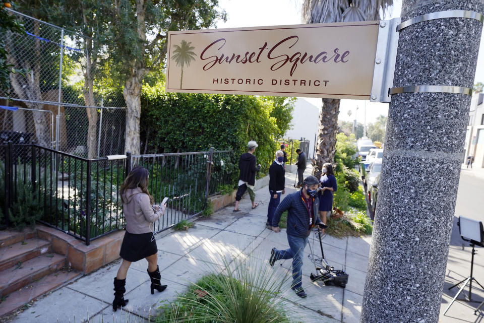 FILE - In this Thursday, Feb. 25, 2021, file photo, members of the media and neighbors walk near an area on North Sierra Bonita Ave. where Lady Gaga's dog walker was shot and two of her French bulldogs stolen in Los Angeles. The woman who returned Lady Gaga’s stolen French bulldogs was among five people arrested in connection with the theft and shooting of the music superstar’s dog walker, Los Angeles police said Thursday, April 29. Detectives do not believe that the thieves knew the dogs belonged to the pop star, the Los Angeles Police Department said in a statement. (AP Photo/Chris Pizzello, File)