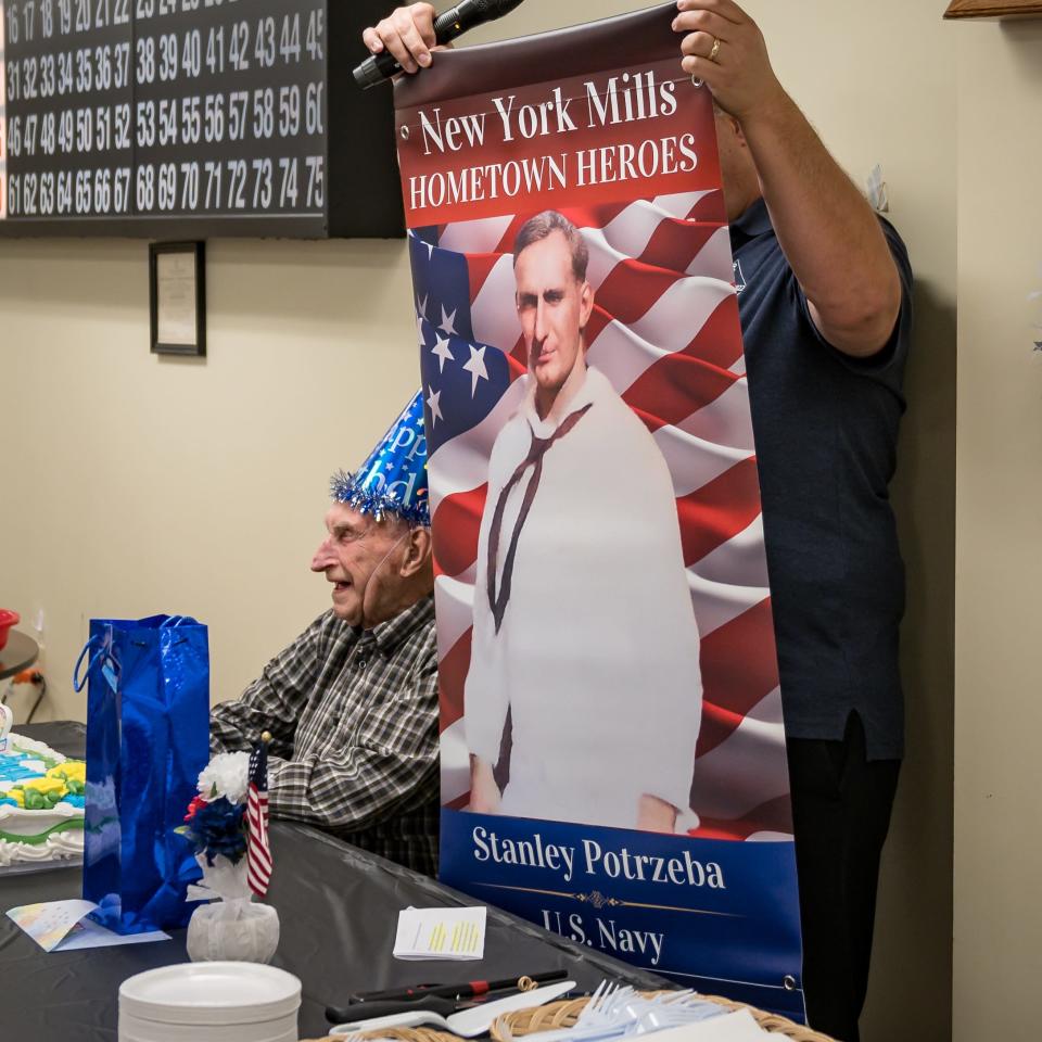 Mayor of New York Mills Ernie Talerico holds up a new Hometown Heroes banner that honors Stanley Potrzeba at the New York Mills Community Center on Tuesday, May 14, 2024.