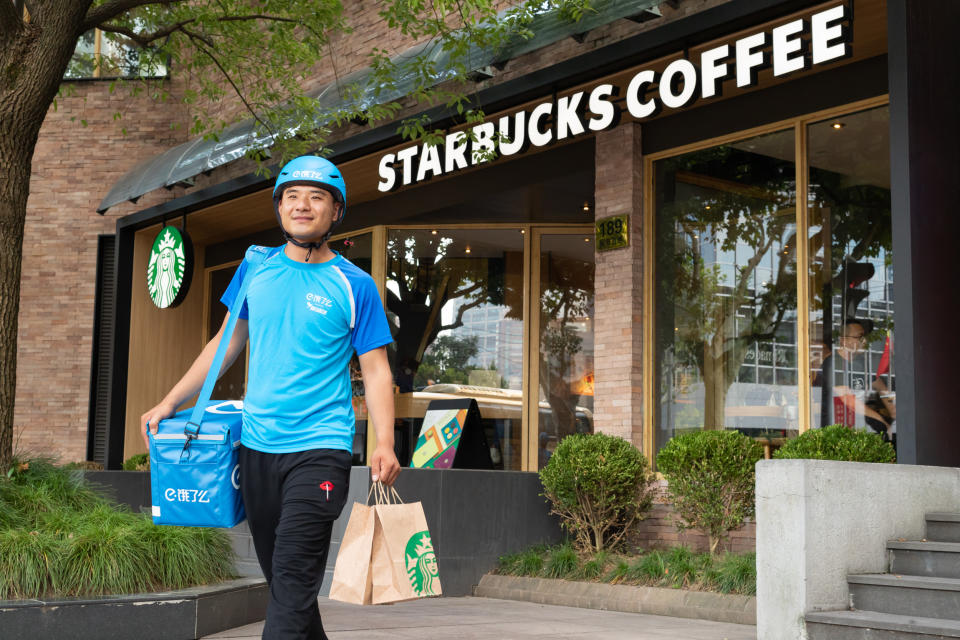 A delivery person carrying items out of a Starbucks cafe