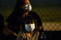 A migrant child from Honduras sits with her mother at an intake area after turning themselves in upon crossing the U.S.-Mexico border Tuesday, May 11, 2021, in La Joya, Texas. The U.S. government continues to report large numbers of migrants crossing the U.S.-Mexico border with an increase in adult crossers. But families and unaccompanied children are still arriving in dramatic numbers despite the weather changing in the Rio Grande Valley registering hotter days and nights. (AP Photo/Gregory Bull)