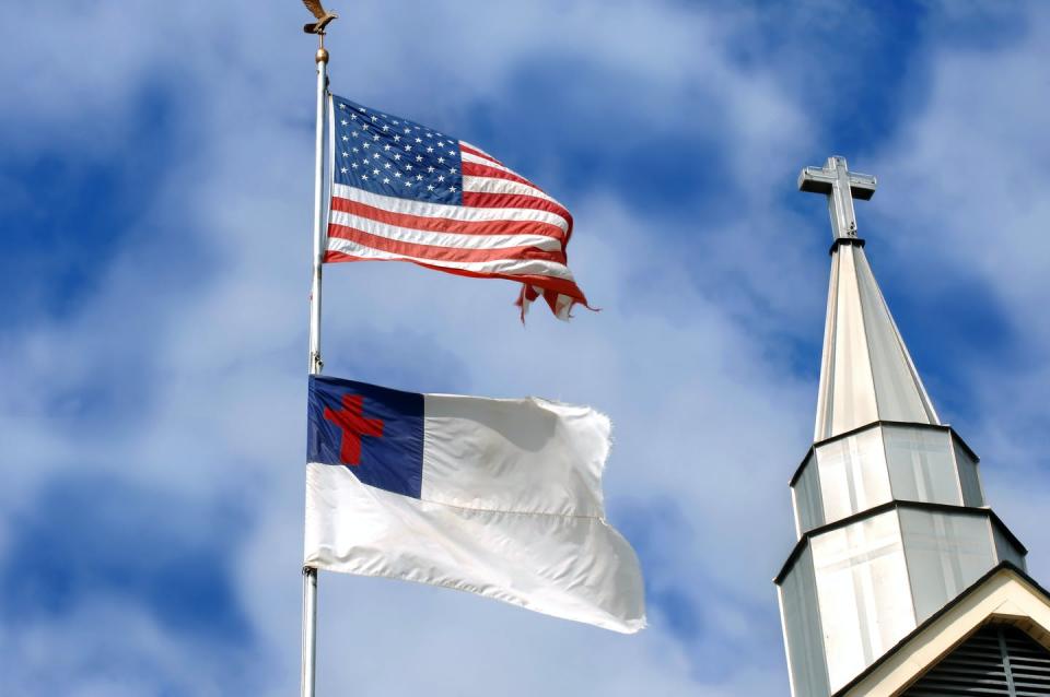 <span class="caption">A Christian flag flies beneath the American flag next to a church steeple.</span> <span class="attribution"><a class="link " href="https://www.gettyimages.com/detail/photo/battle-weary-royalty-free-image/157034896?adppopup=true" rel="nofollow noopener" target="_blank" data-ylk="slk:nameinfame/iStock via Getty Images Plus;elm:context_link;itc:0;sec:content-canvas">nameinfame/iStock via Getty Images Plus</a></span>