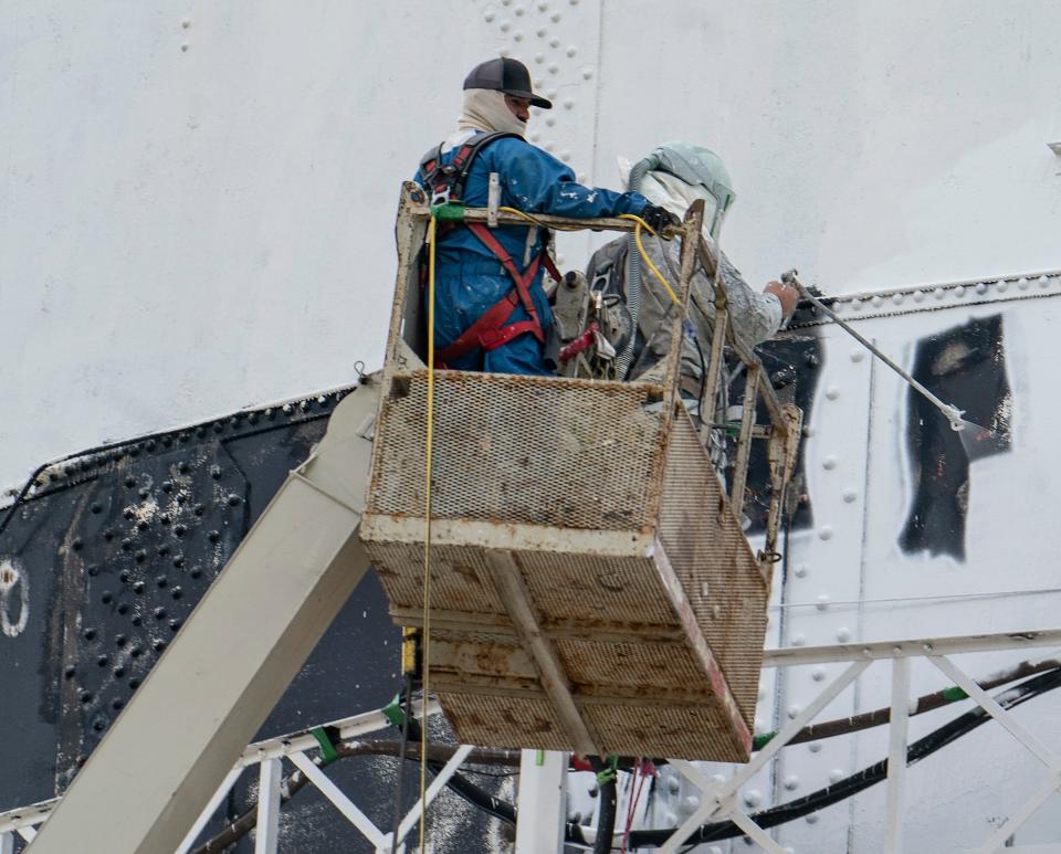 Mike Moran, owner of Protective Coatings Epoxy Systems in Fowlerville, left, leans in with a sprayer as Guy Bajis, right, assists on the iconic Detroit Zoo water tower in Royal Oak that is getting a facelift Thursday, June 22, 2023.