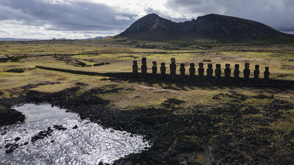 Moai statues stand o Ahu Tongariki near the Rano Raraku volcano, top, on Rapa Nui, or Easter Island, Chile, Sunday, Nov. 27, 2022. Each monolithic human figure carved centuries ago by this remote Pacific island's Rapanui people represents an ancestor. (AP Photo/Esteban Felix)