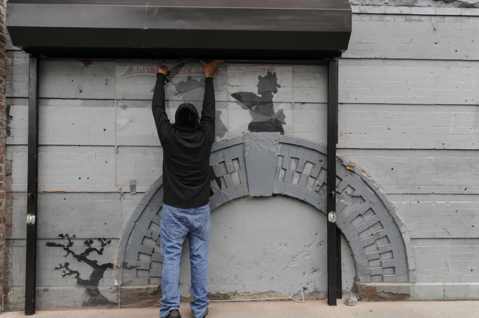 Feliciano Perez opens the gate to reveal the work by British graffiti artist Banksy on Saturday, Oct. 19, 2013, in the Brooklyn borough of New York. The building owner has hired security guards and installed a metal gate to protect a work by Banksy. Cara Tabachnick, whose family owns the building, said the goal is to preserve the artwork "so it can be viewed and enjoyed." Most of the Banksy works that have gone up have been tagged over by others, and some have been completely erased. Mayor Michael Bloomberg said last week that graffiti ruins property and is "a sign of decay." (AP Photo/Alyssa Goodman)