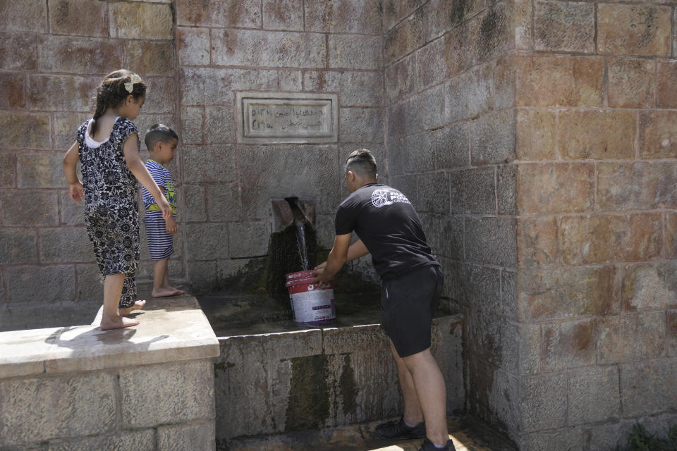 A Palestinian collects water from a spring in the West Bank village of Battir Sunday, June 4, 2023. Environmental groups say an Israeli settlement project slated for a nearby hilltop could threaten the ancient terraces of the village, which has been recognized as a UNESCO world heritage site. (AP Photo/Mahmoud Illean)