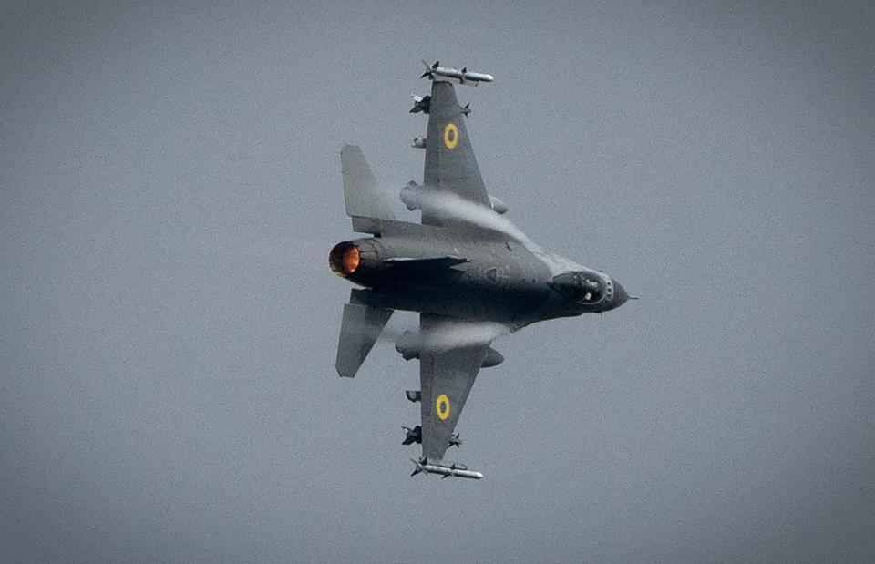 A Ukrainian air force F-16 fighter jet banking across grey skies.