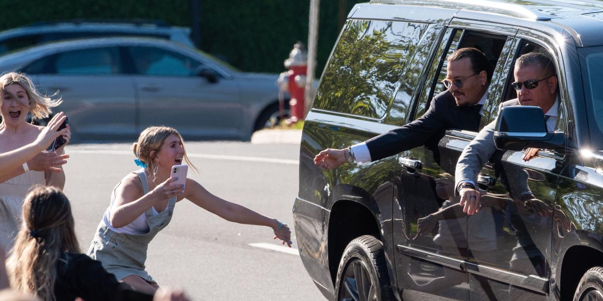 A female fan reaches out her hand to Johnny Depp who is in a car.