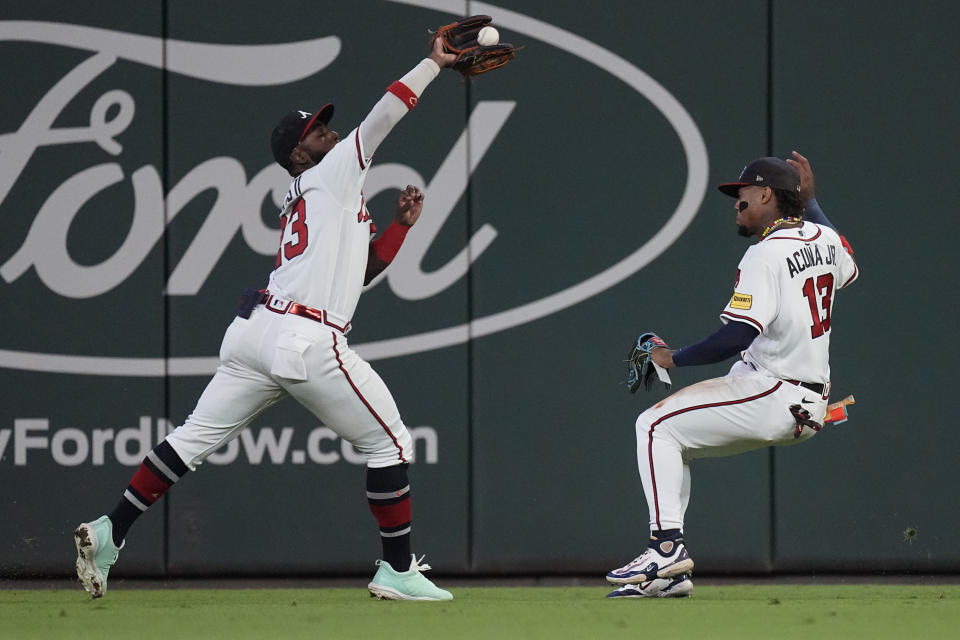 Atlanta Braves center fielder Michael Harris II (23) crosses right fielder Ronald Acuna Jr. (13) as he catches a fly ball from Chicago Cubs' Ian Happ in the 10th inning of a baseball game, Wednesday, Sept. 27, 2023, in Atlanta. (AP Photo/John Bazemore)