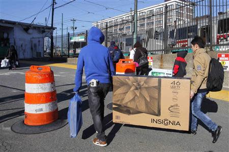 Two men carry a newly purchased television to a subway stop in Cambridge, Massachusetts November 29, 2013. Black Friday, the day following the Thanksgiving Day holiday, has traditionally been the busiest shopping day in the United States. REUTERS/Brian Snyder