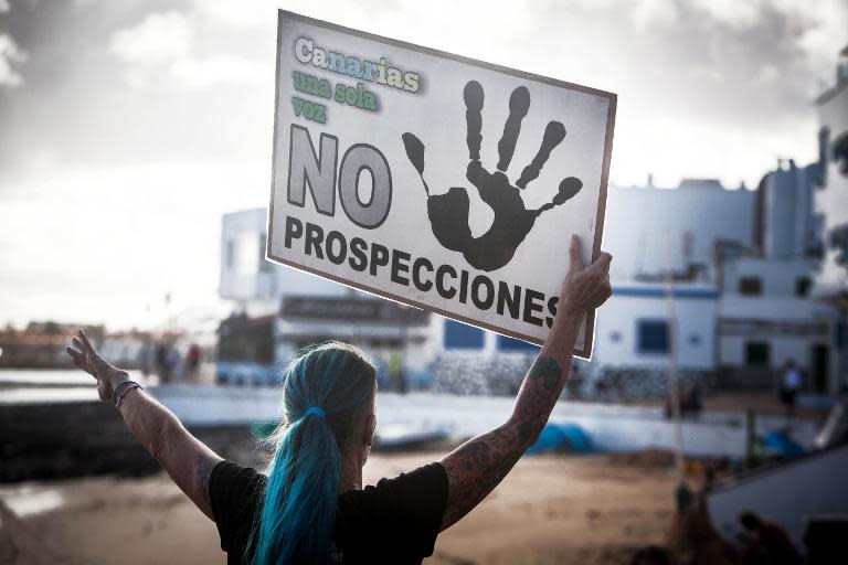 A woman holds a placard reading "Canaries, only one voice: No prospections" as she invites tourists to take part in the protest against oil exploration, in Corralejo, on November 30, 2014