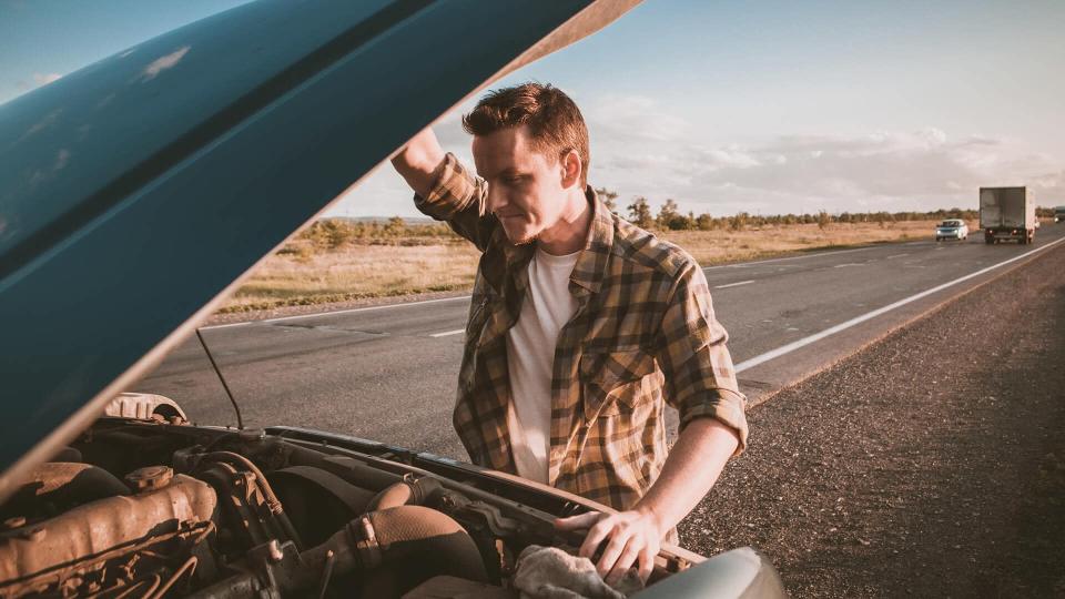 man with broken down car on highway