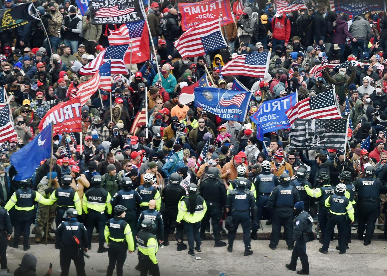 Security forces identifiable by their lime-green shirts, and wearing jackets marked Police, confront a melee of people carrying Trump flags.