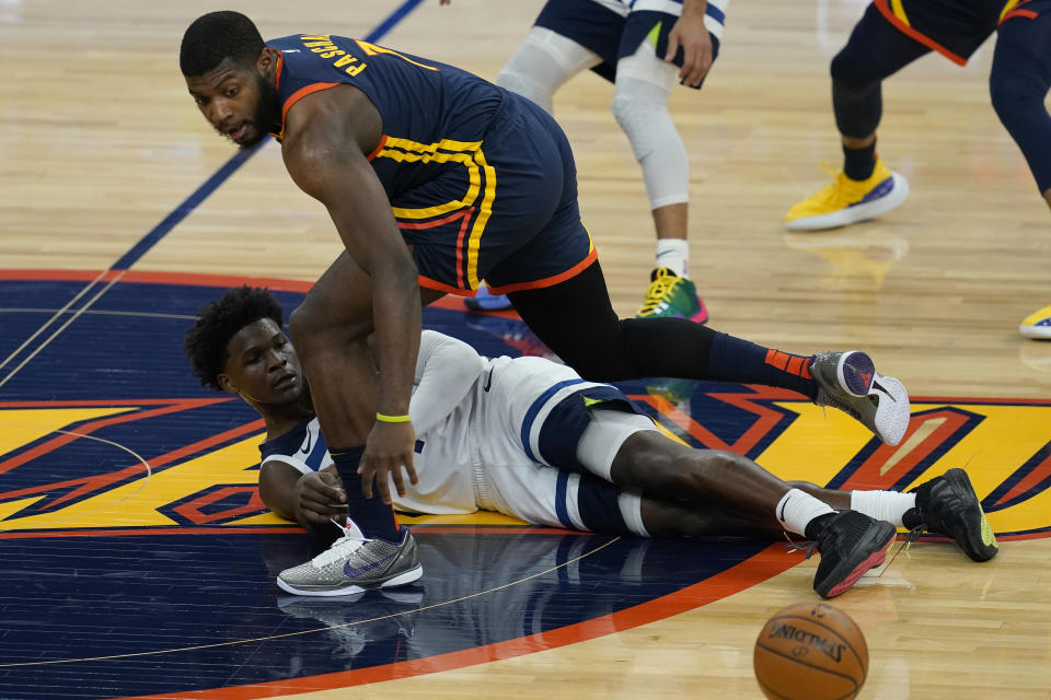 Minnesota Timberwolves guard Anthony Edwards, bottom, passes the ball under Golden State Warriors forward Eric Paschall during the first half of an NBA basketball game in San Francisco, Wednesday, Jan. 27, 2021. (AP Photo/Jeff Chiu)