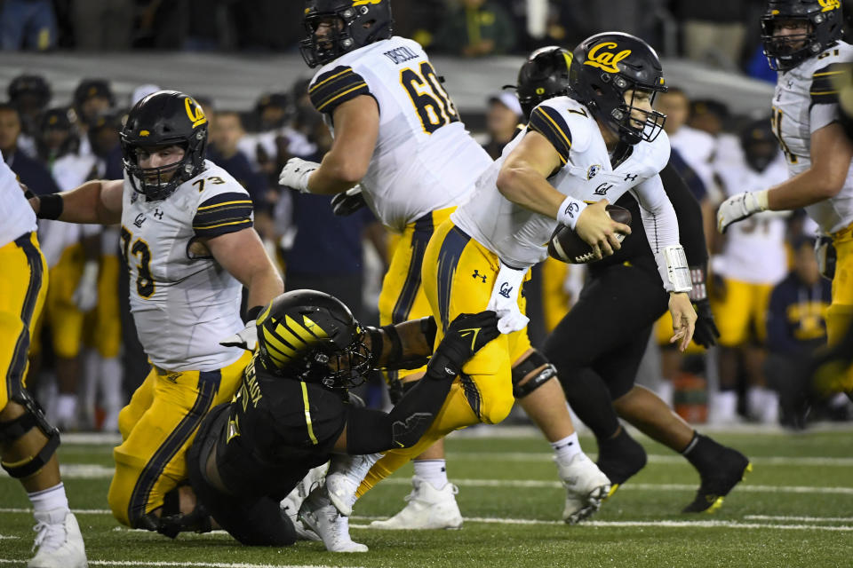 California quarterback Chase Garbers (7) works to escape the grasp of Oregon defensive end Kayvon Thibodeaux (5) during the fourth quarter of an NCAA college football game Friday, Oct. 15, 2021, in Eugene, Ore. (AP Photo/Andy Nelson)